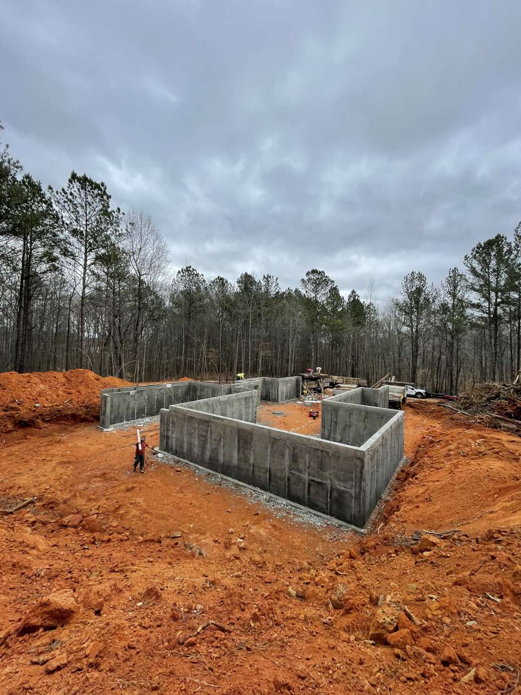 Poured concrete basement walls standing on a red clay lot in the woods